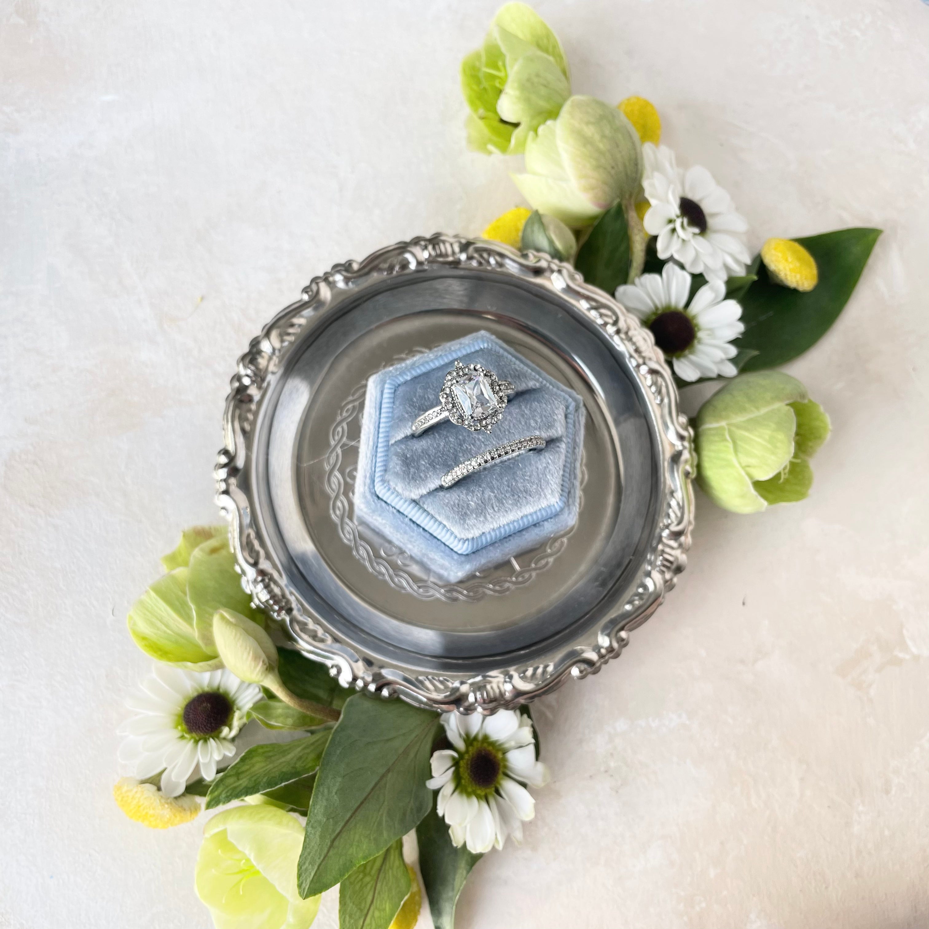 Dusty blue ring box on silver dish with white and green florals - Wedding Flat lay props from Champagne & GRIT