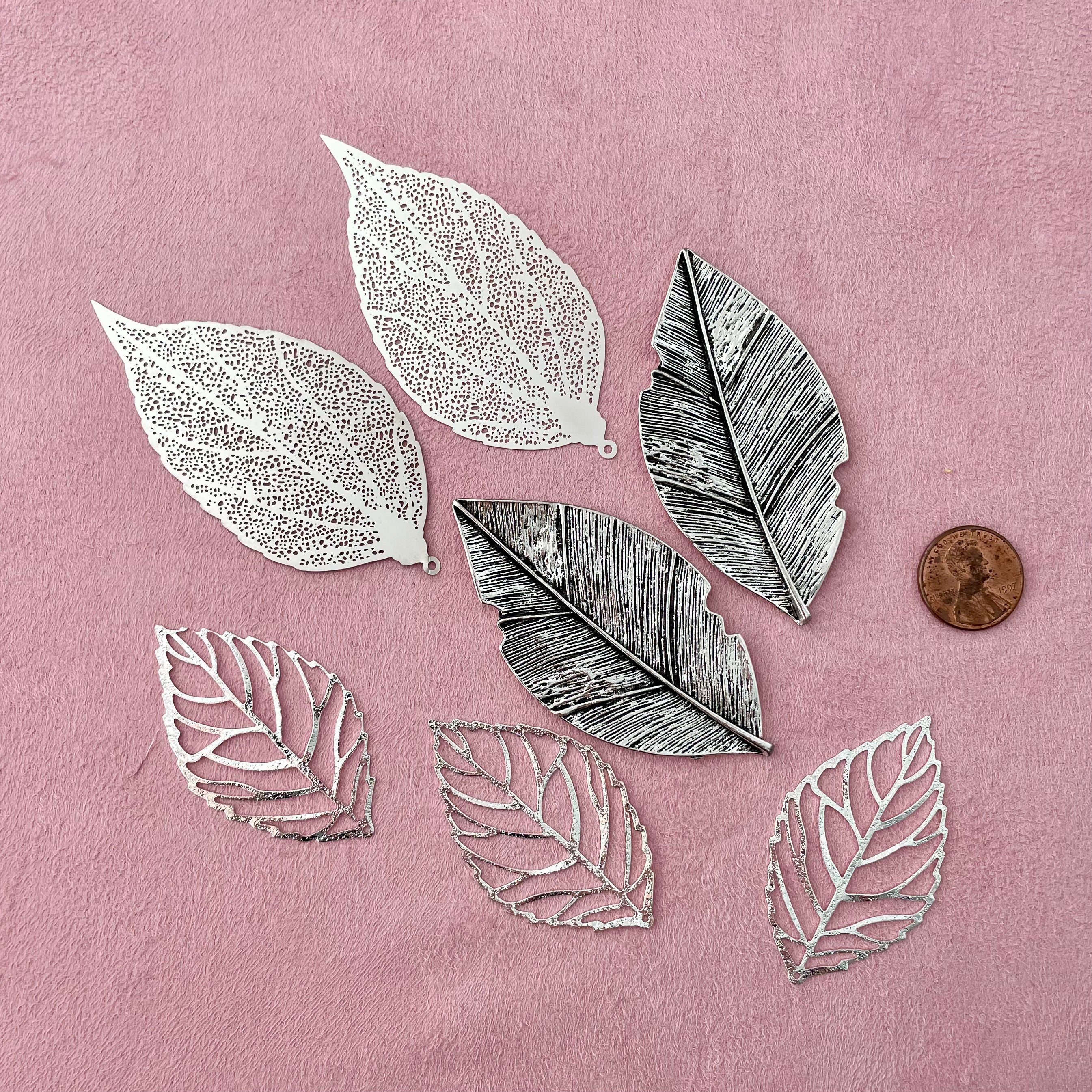 7 styling leaves including 3 silver leaves, 2 silver leaves that are larger, and 2 large silver with dark accent leaves with penny beside for size reference - wedding flat lay props from Champagne & GRIT