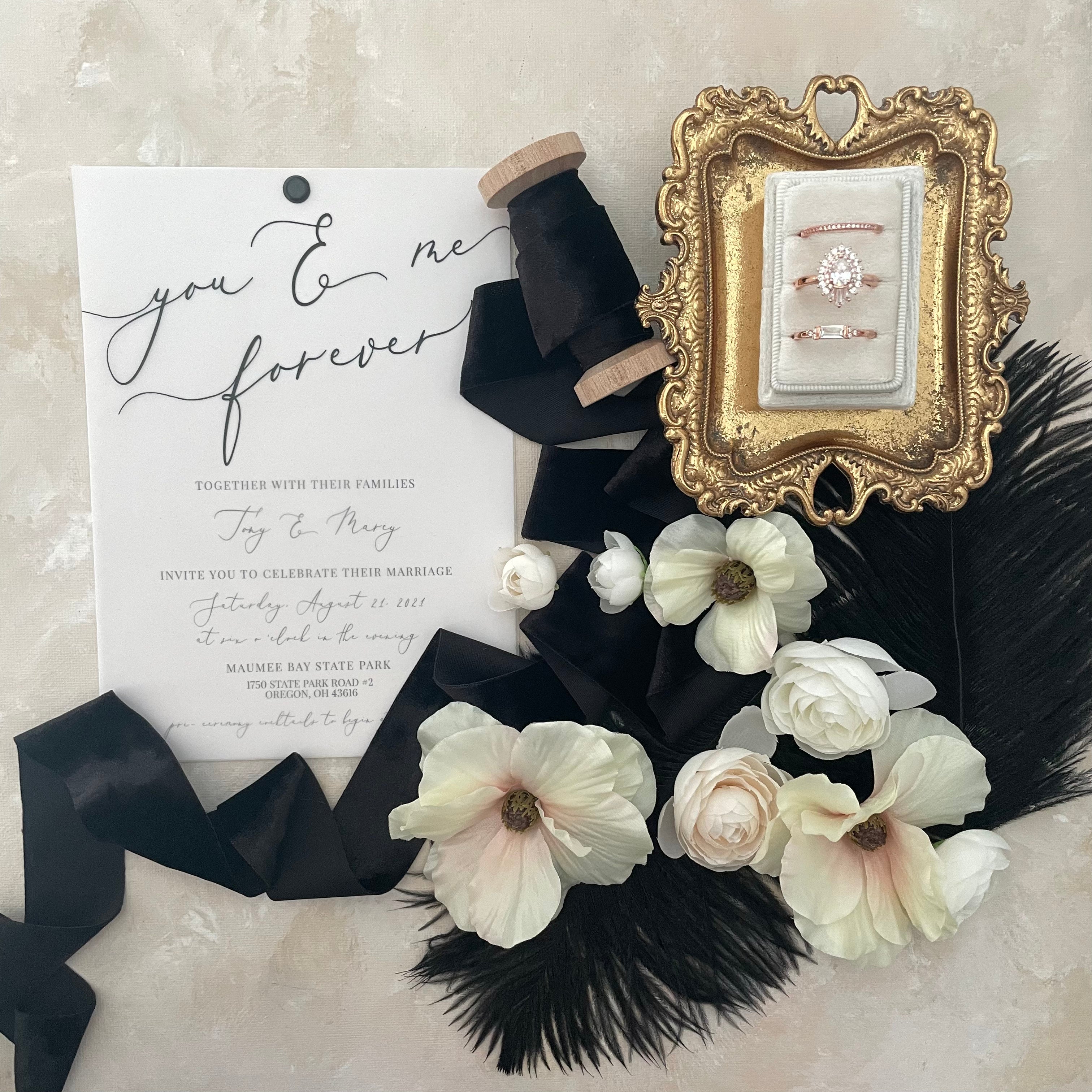 Black velvet ribbon styled with white triple slot ring box, wedding invitation and florals  -  Wedding Flat lay props from Champagne & GRIT