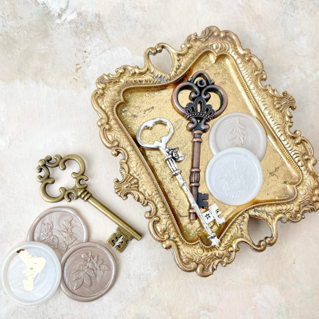 Gold vintage tray with silver key and bronze key, and 2 neutral wax seals. Beside tray is three more wax seals and one gold key - Flat Lay Props from Champagne & GRIT