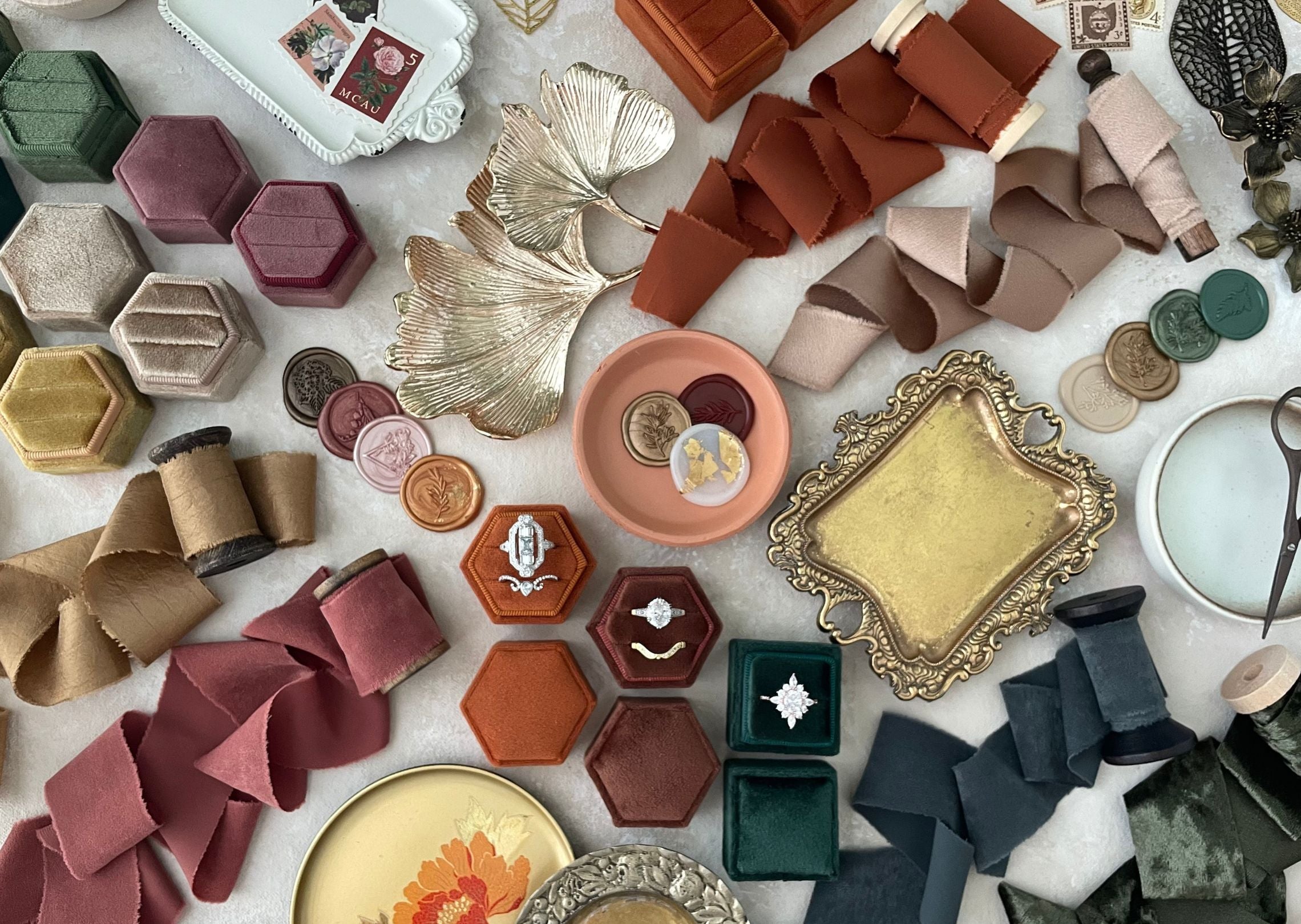 fall flatlay props, ribbons, Ring boxes, wax seals, Ring dishes, vintage plated all in a warm a color fall color pallet.