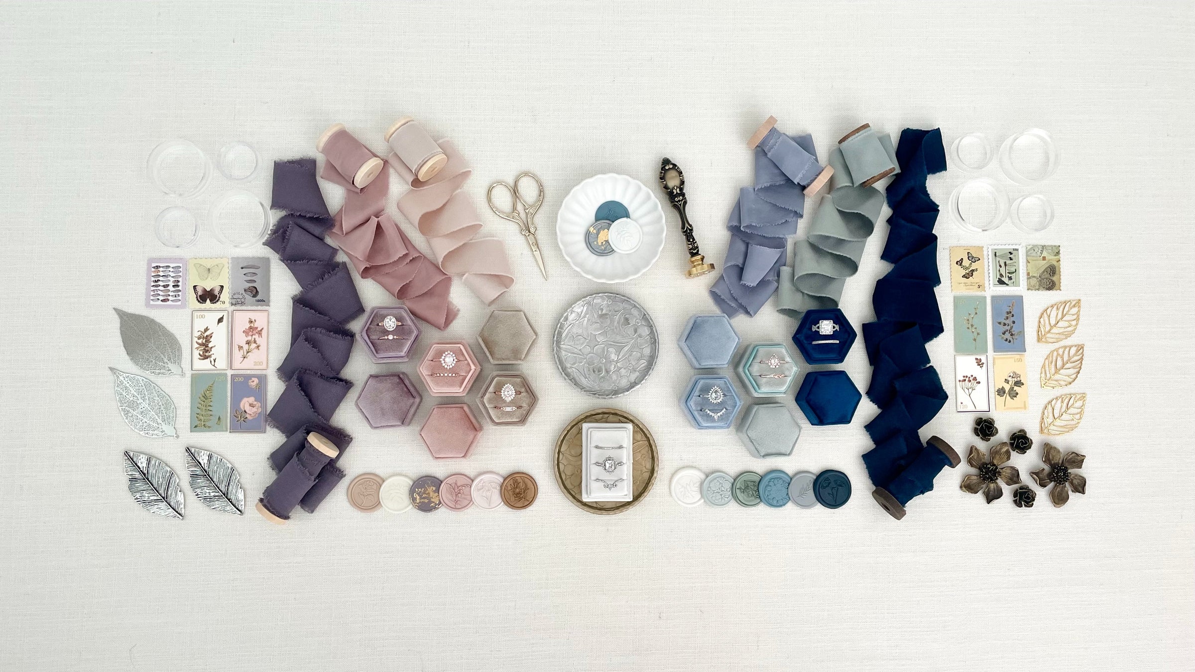 Silver, Plum, Lavender, Dusty Pink, Gold, Vintage blue, NAvy Blue, and Tan styling kits laid out beside each other on a white styling mat from Champagne & GRIT