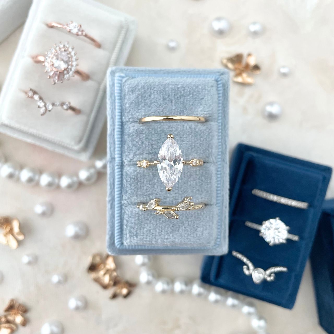 3 rectangle ring boxes.  white, navy and dusty blue, styled with pearls and mini golden flowers