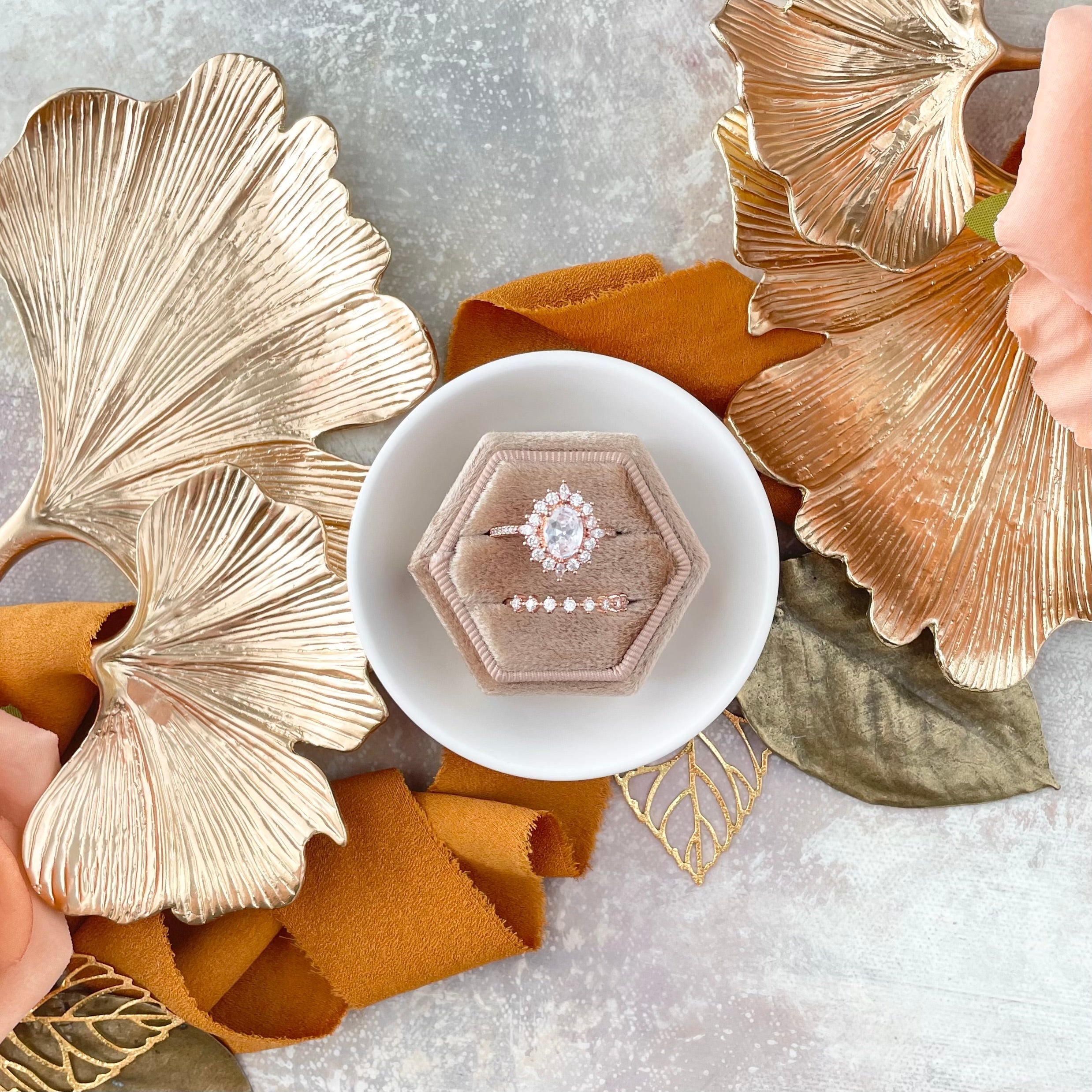 Close up of Ginkgo Leaf Gold Styling Tray styled with floral wedding invitation, tan ring box, orange ribbon, and blush florals - Flat Lay Props from Champagne & GRIT