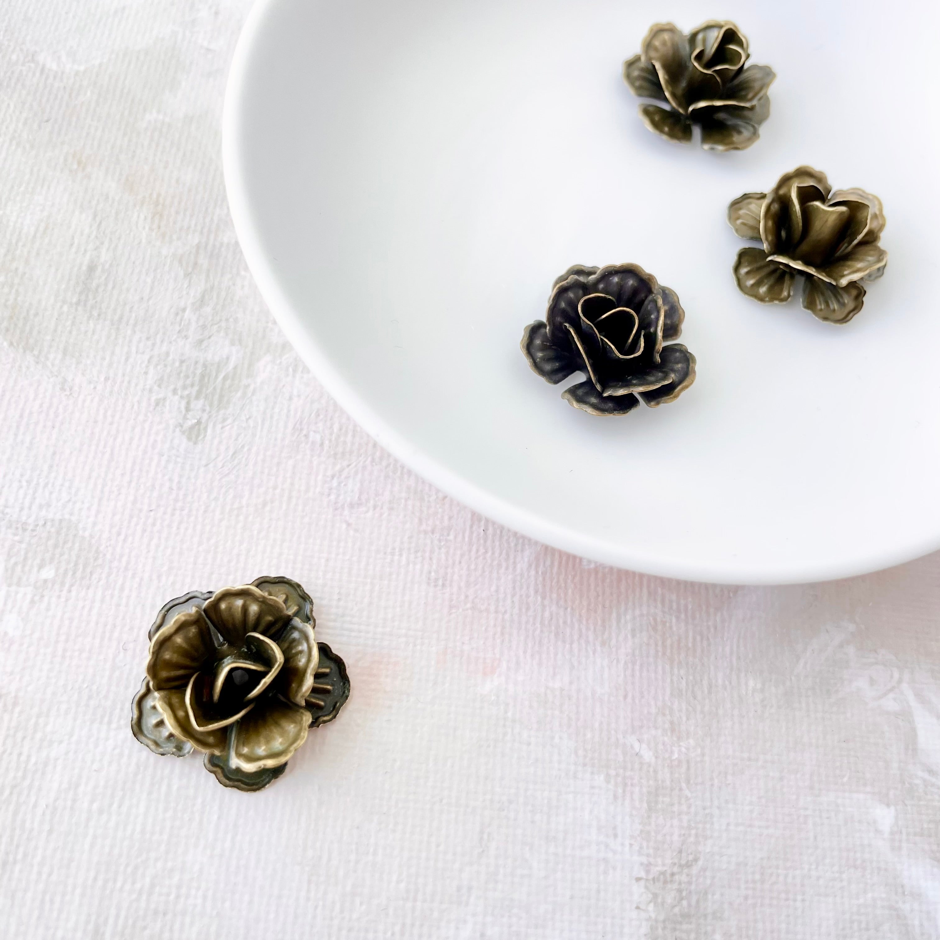 Close up of 4 small metal styling flowers  - Flat lay props from Champagne & GRIT