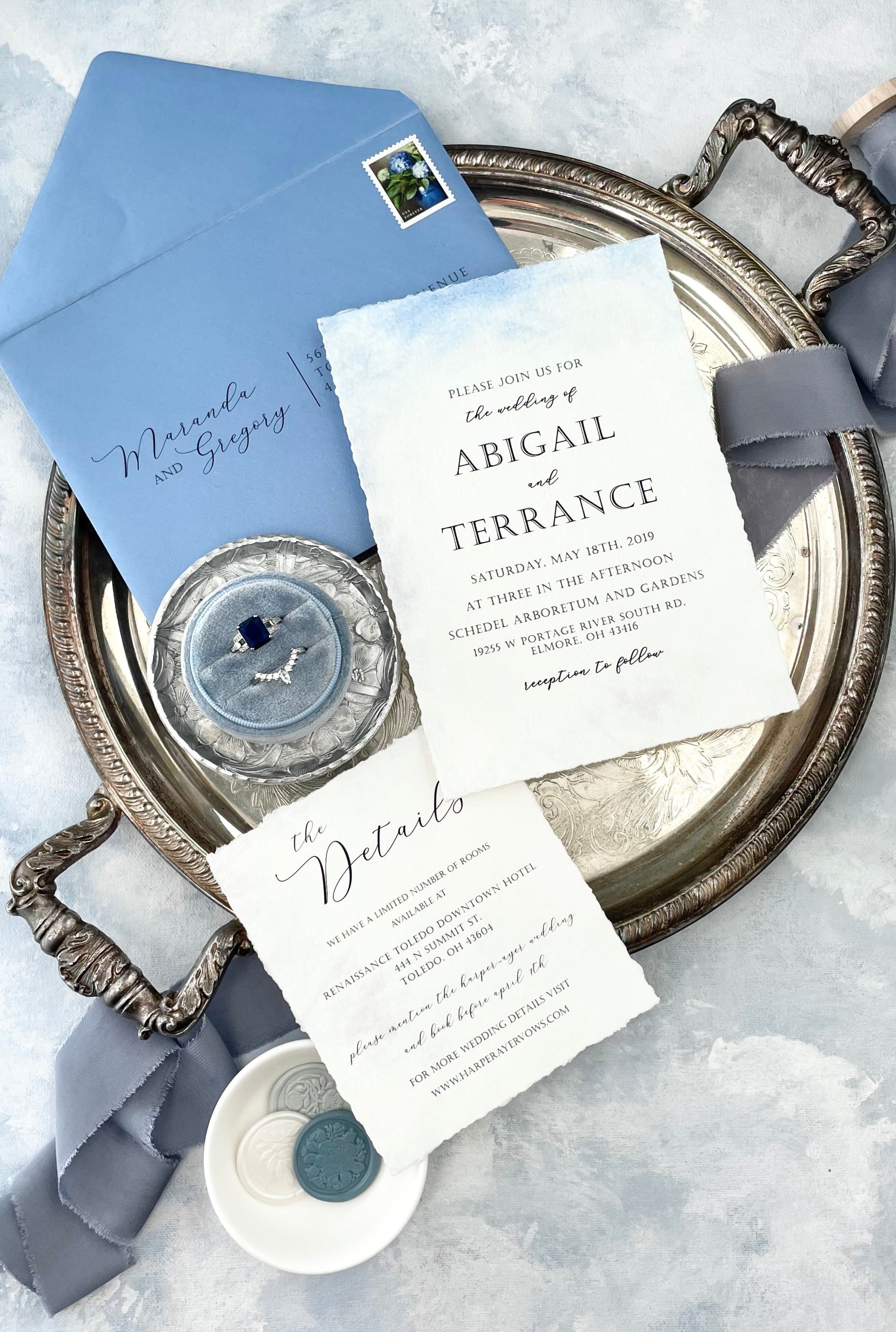 Dusty Blue Ribbon, styled with dusty blue flat lay styling kit, white wedding invitation with blue envelope and dusty blue ring box on silver tray - wedding flat lay props from Champagne & GRIT