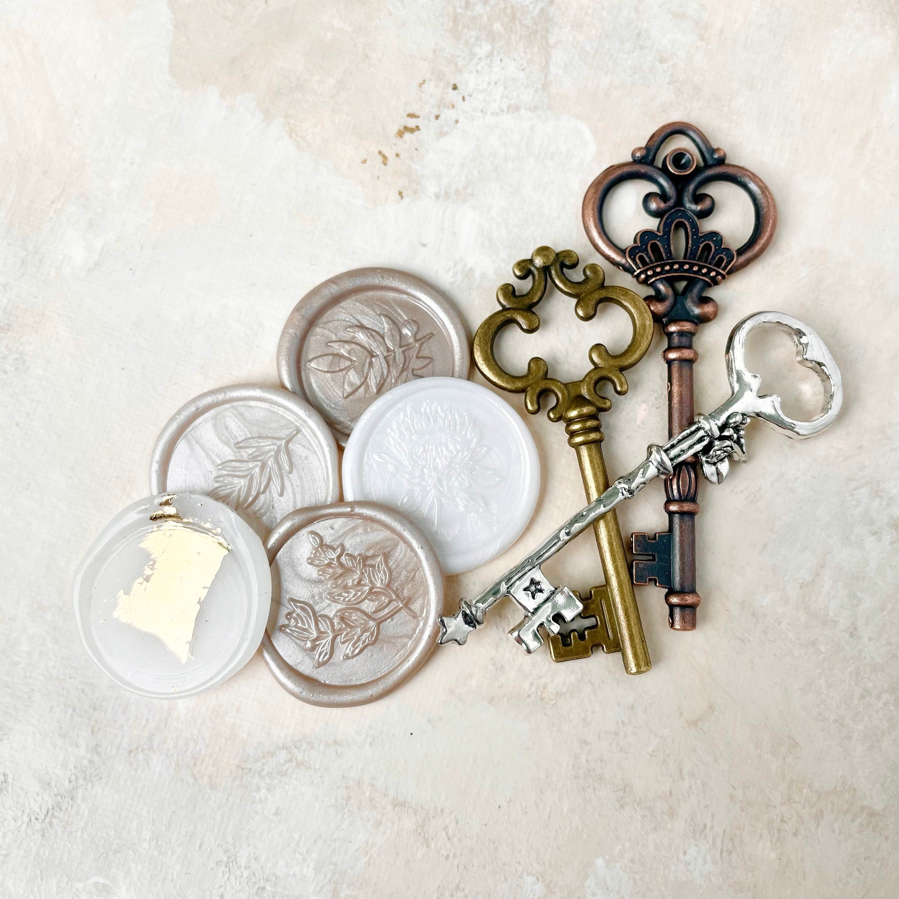5 champagne and ivory wax seals beside one gold key, one bronze key, and one silver key these are must have flat lay props from Champagne & GRIT