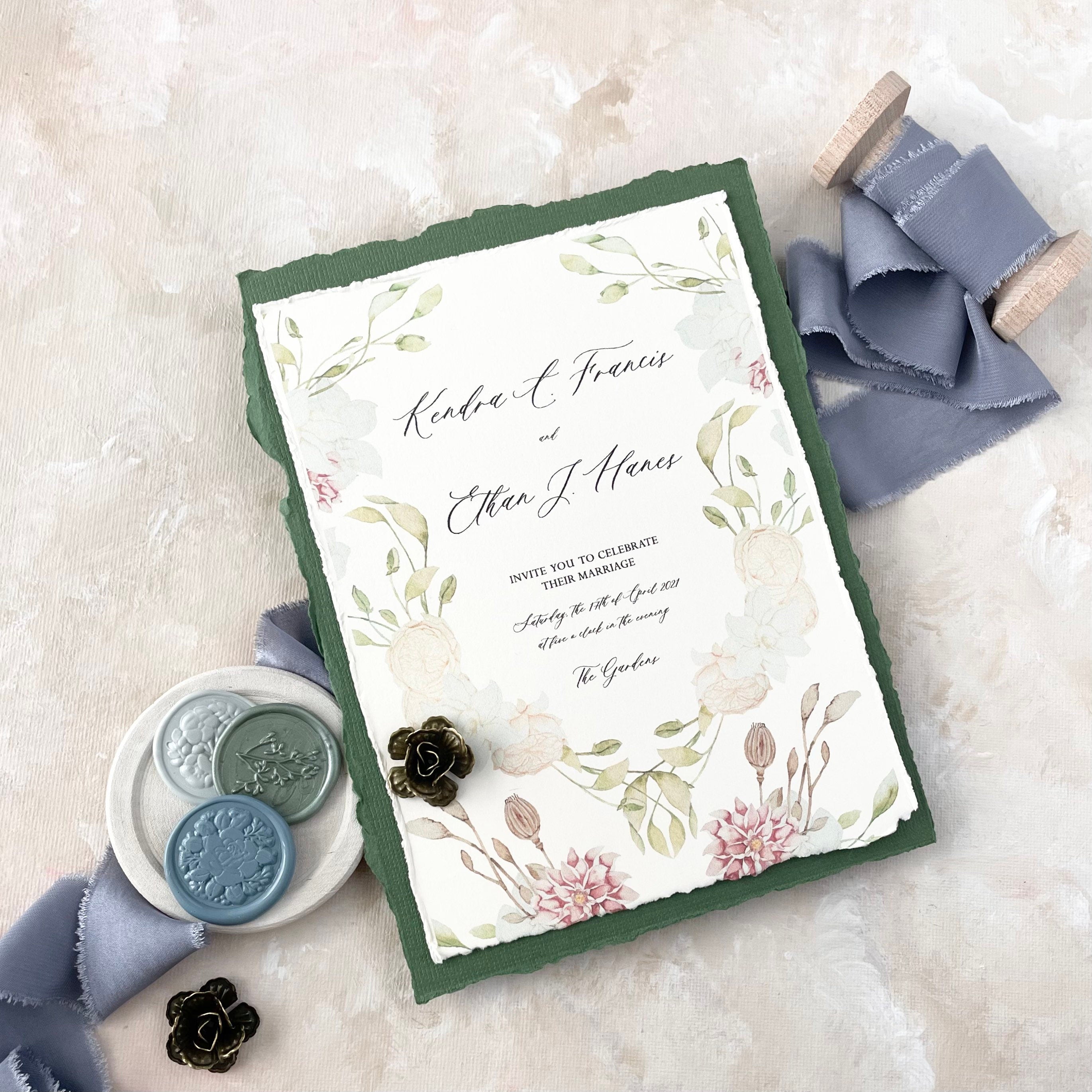 Floral wedding invitation styled with dusty blue ribbon, 3 wax seals in white dish, and two bronze styling flowers -  Flat lay props from Champagne & GRIT 