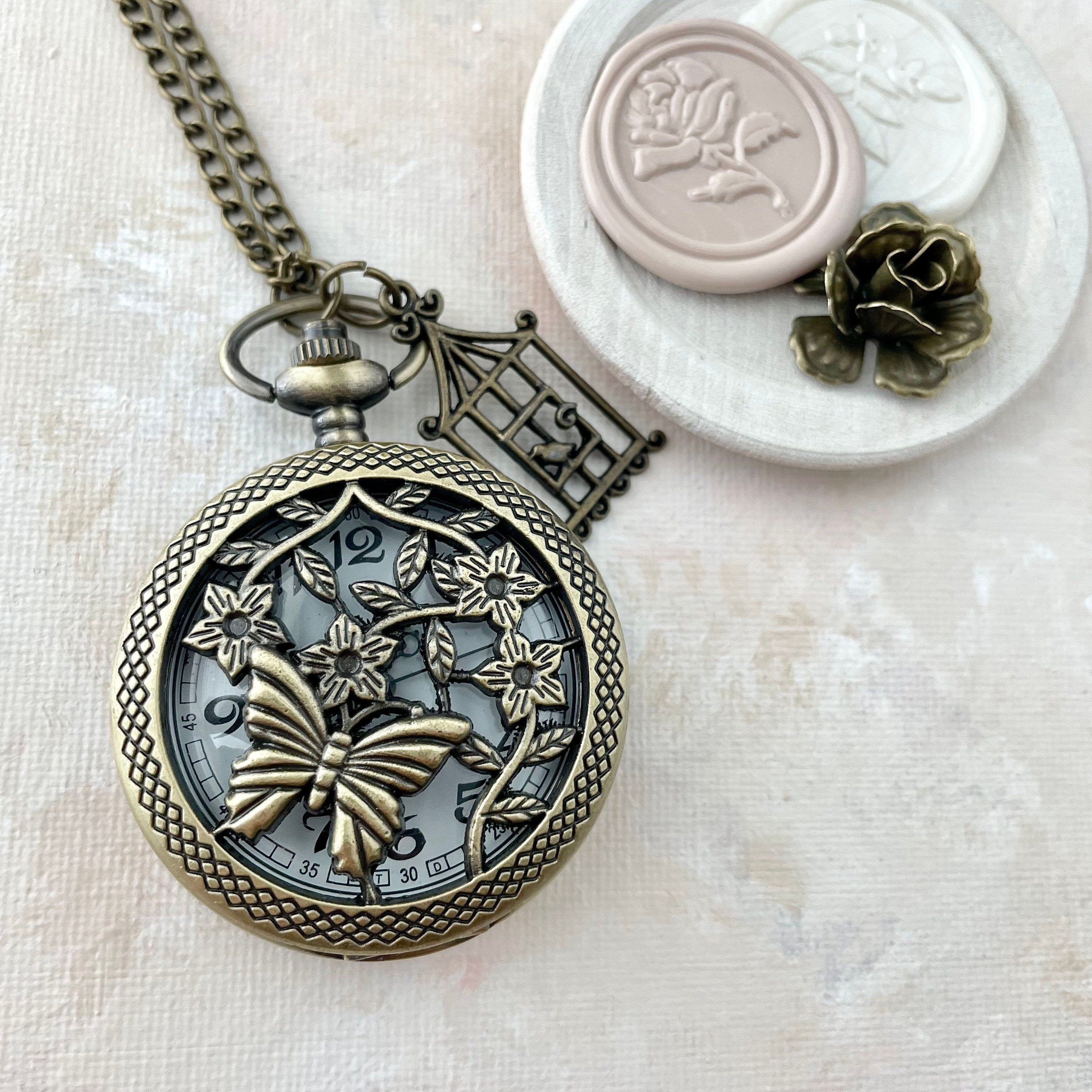 Vintage pocket watch styled with 2, neutral wax seals in white dish and one mini bronze styling flower -  Flat lay props from Champagne & GRIT