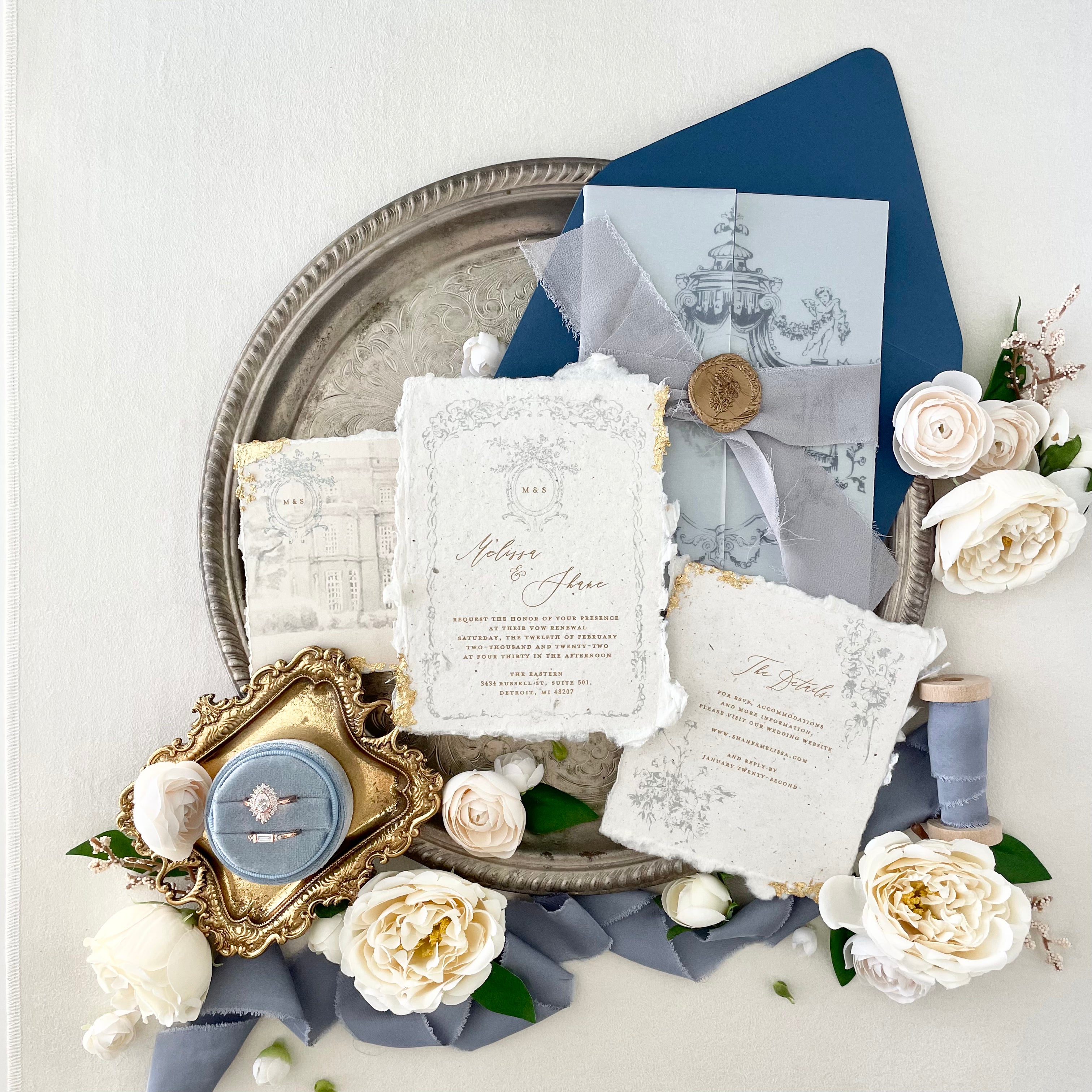 Gold vintage tray for wedding flay lay styled with Dust Blue Ring Box, Dusty blue ribbon, white florals, and wedding invitation with gold wax seal and navy blue envelope  - Flat Lay Props from Champagne & GRIT