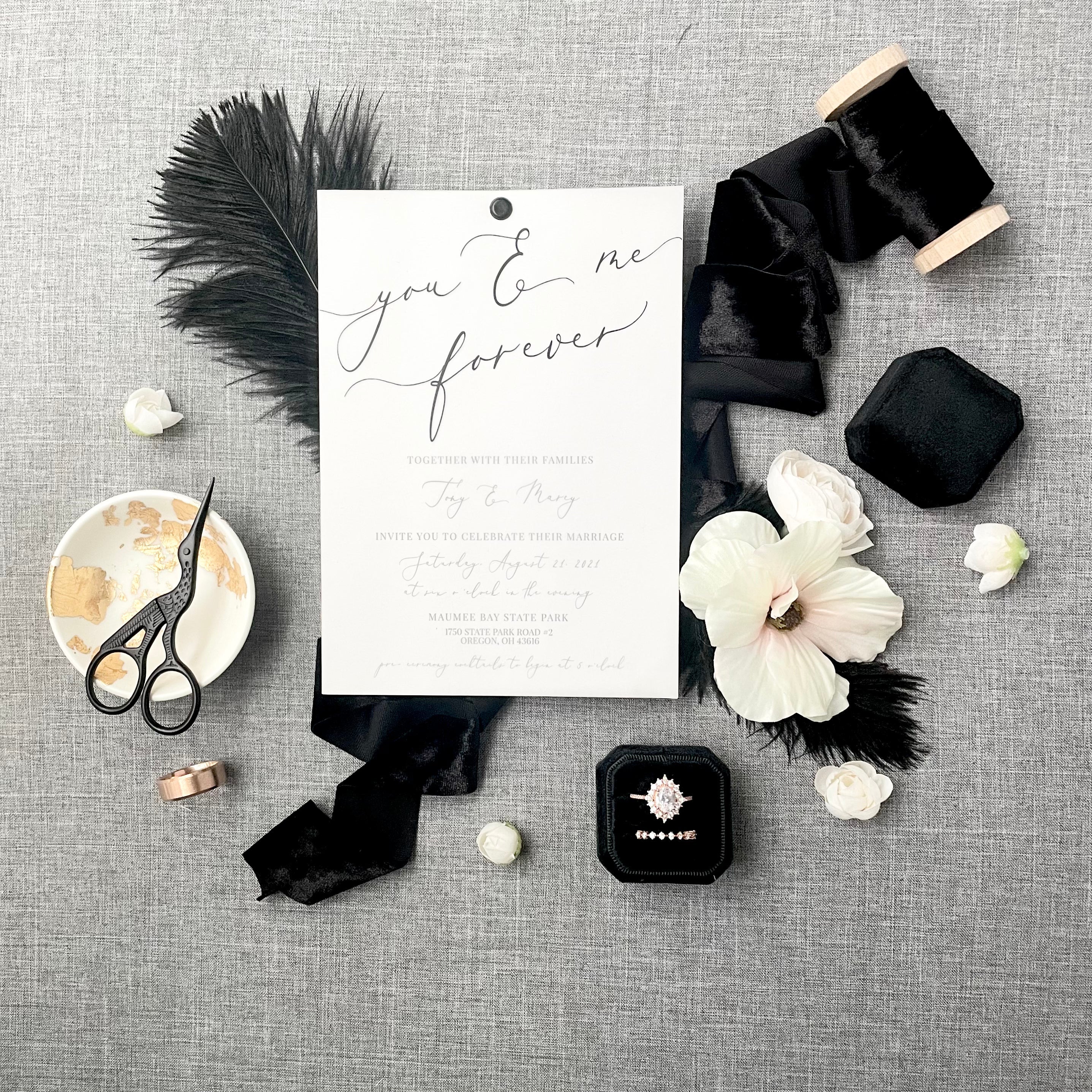 Black velvet ribbon styled with black ring box, wedding invitation, black scissors and florals  -  Wedding Flat lay props from Champagne & GRIT