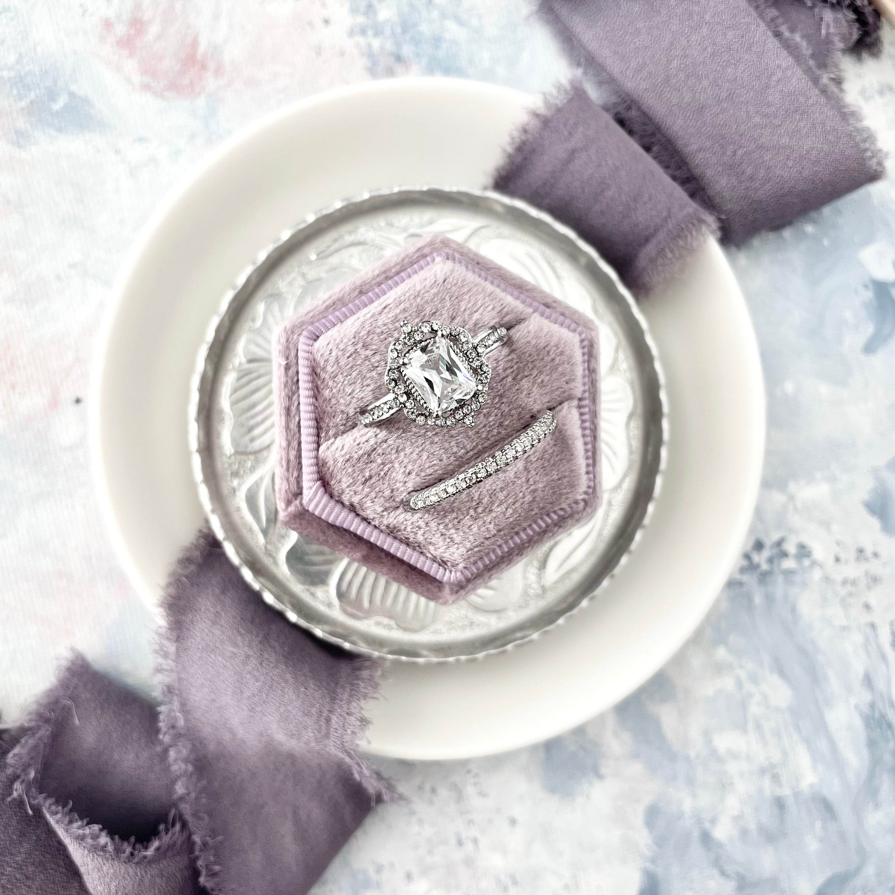 Lavendar ring box on silver dish with lavender ribbon and a larger white dish - Flat lay props from Champagne & GRIT
