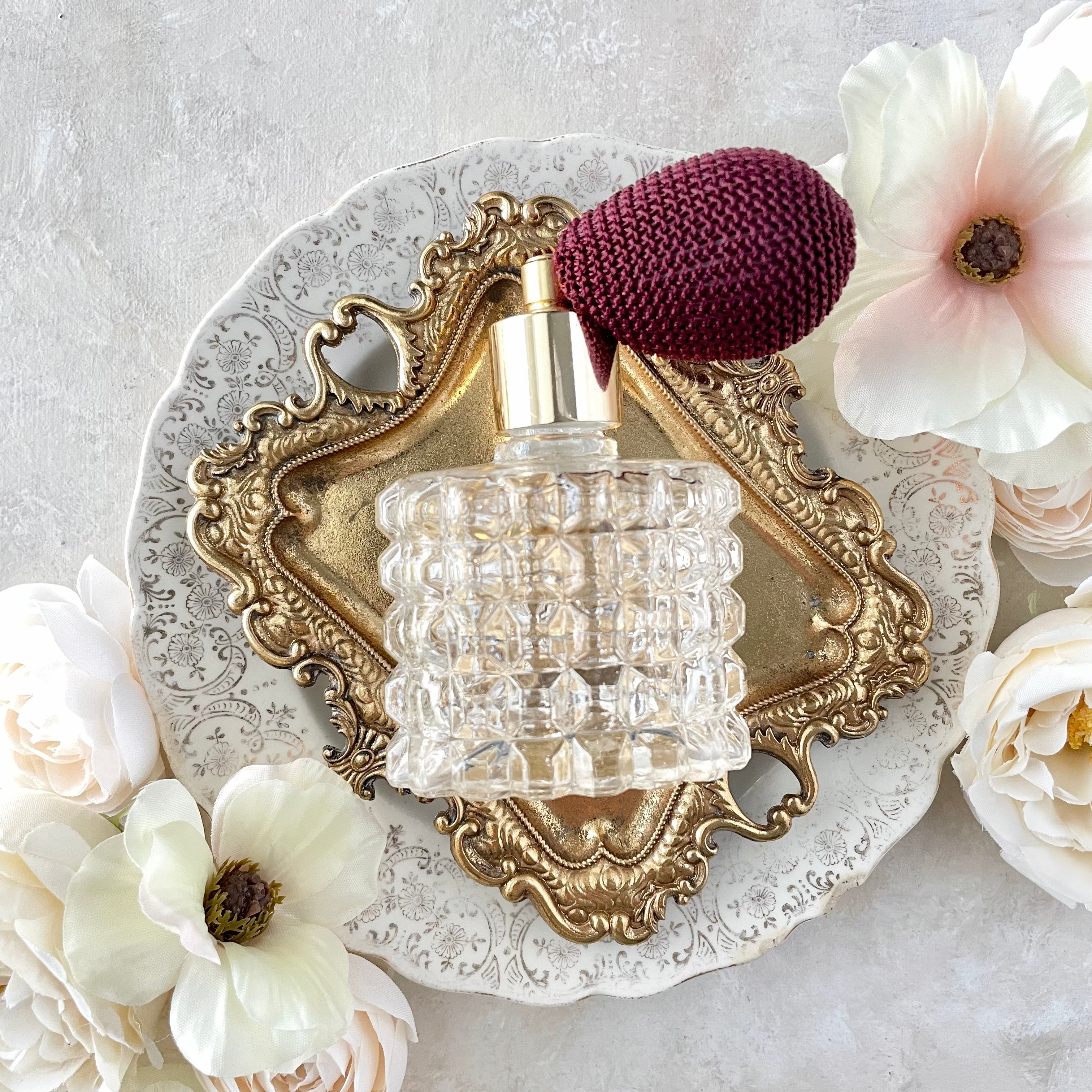 Gold vintage tray with vintage perfume bottle on top surrounded by white florals - Flat Lay Props from Champagne & GRIT