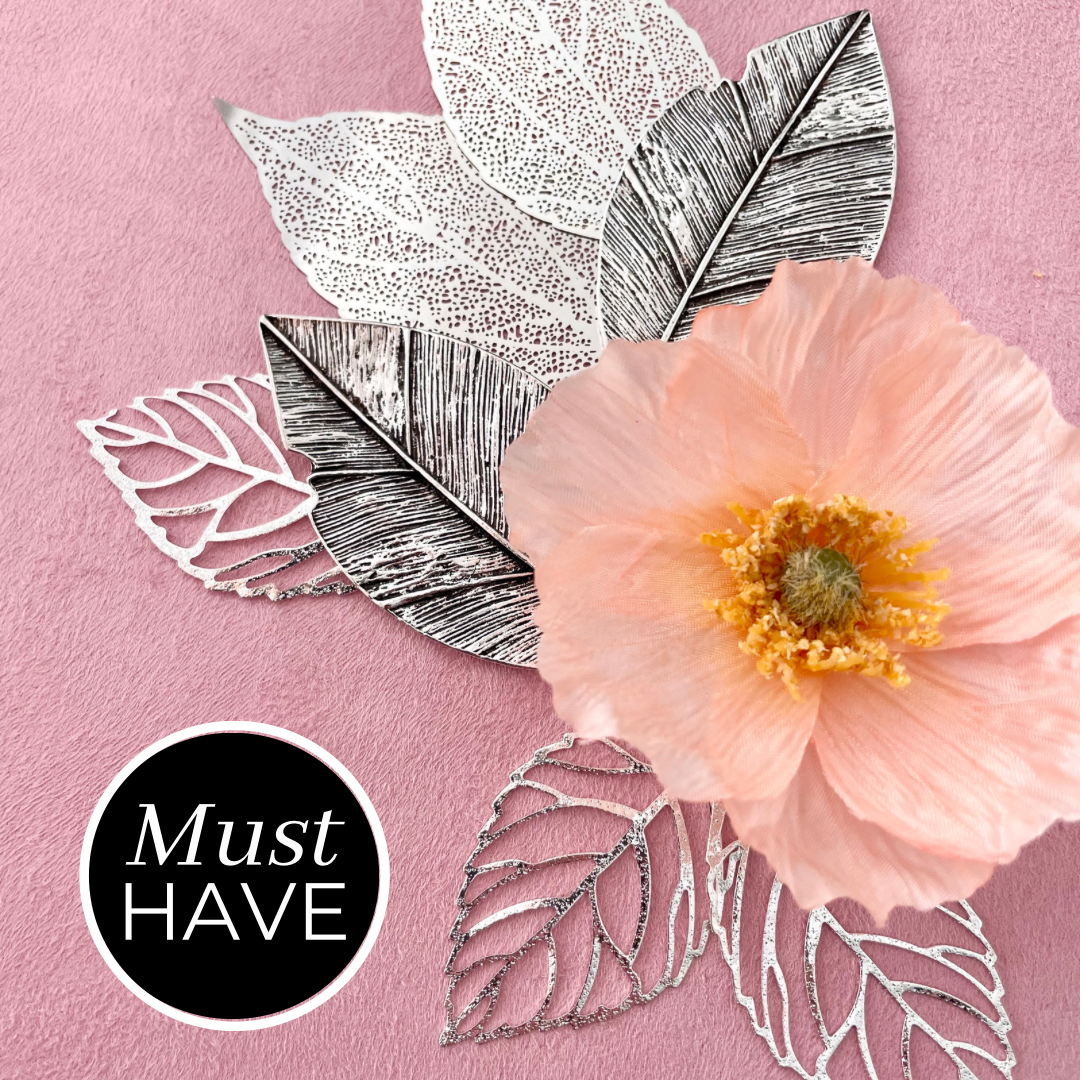 7 styling leaves including 3 silver leaves, 2 silver leaves that are larger, and 2 large silver with dark accent leaves with one flower on top - must have wedding flat lay props from Champagne & GRIT
