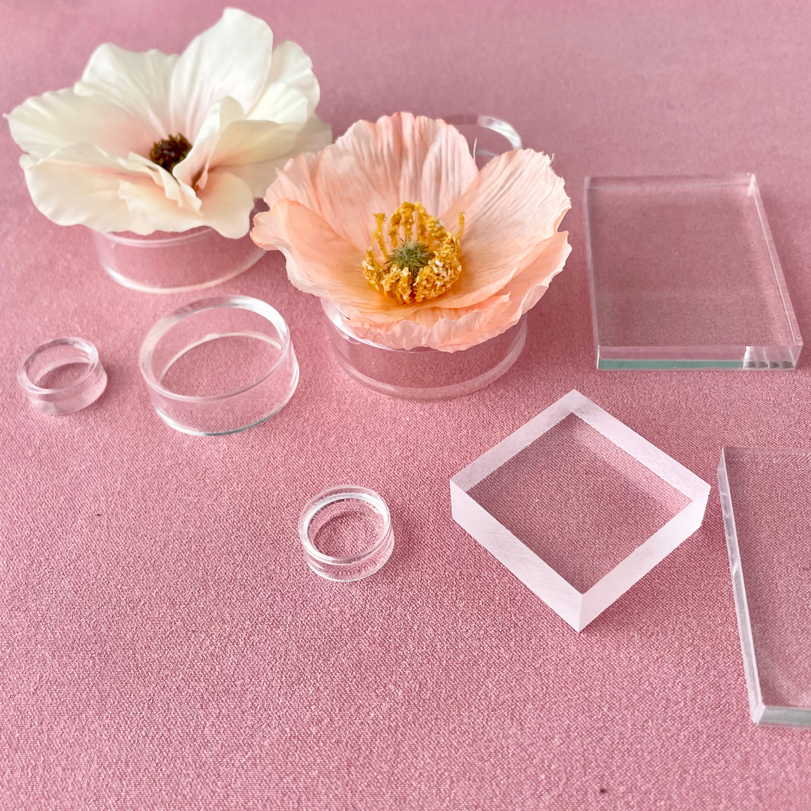 Close up side angle image of Clear Acrylic Styling Block Set & Floral Risers for Flat Lays on a Dusty Pink Styling Mat from Champagne & GRIT