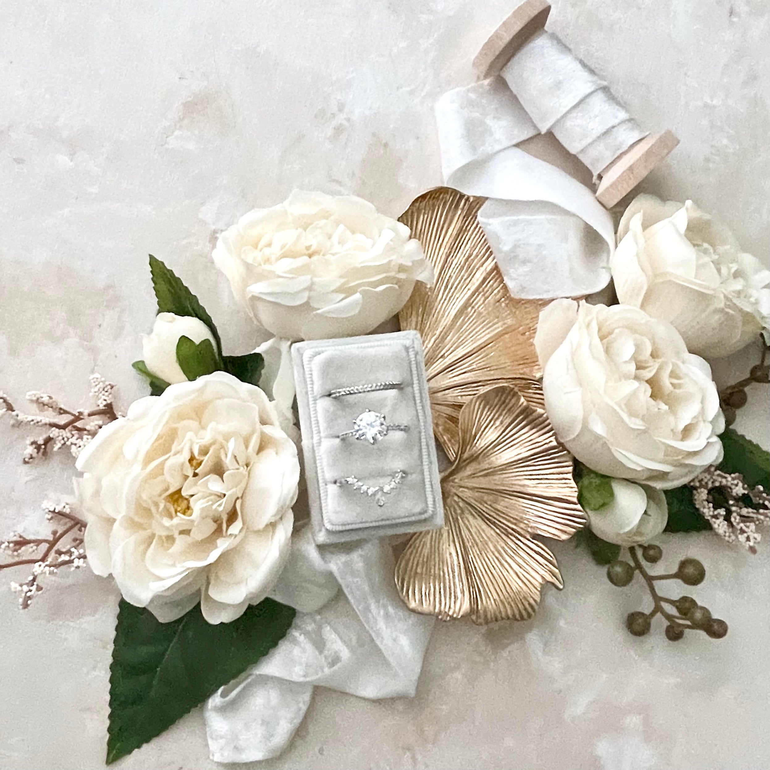 Ginkgo Leaf Gold Styling Tray along side a silver ring box, silver ribbon, and ivory florals - Flat Lay Props from Champagne & GRIT