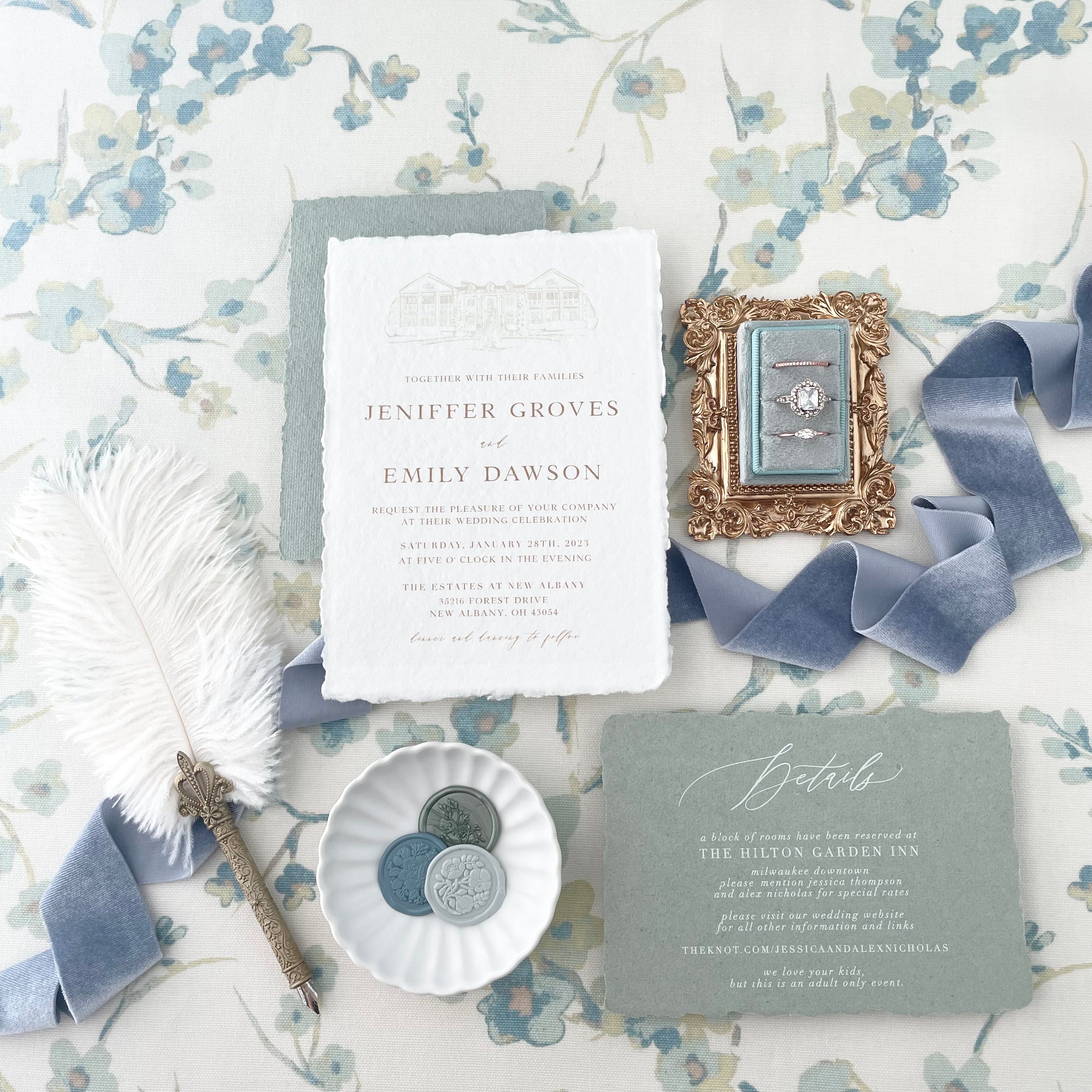 Vintage feather pen and sage green and white wedding invitation styled with dusty blue ring box on gold tray, dusty blue ribbon, and 3 wax seals on Matte white scalloped dish  - wedding flat lay props from Champagne & GRIT