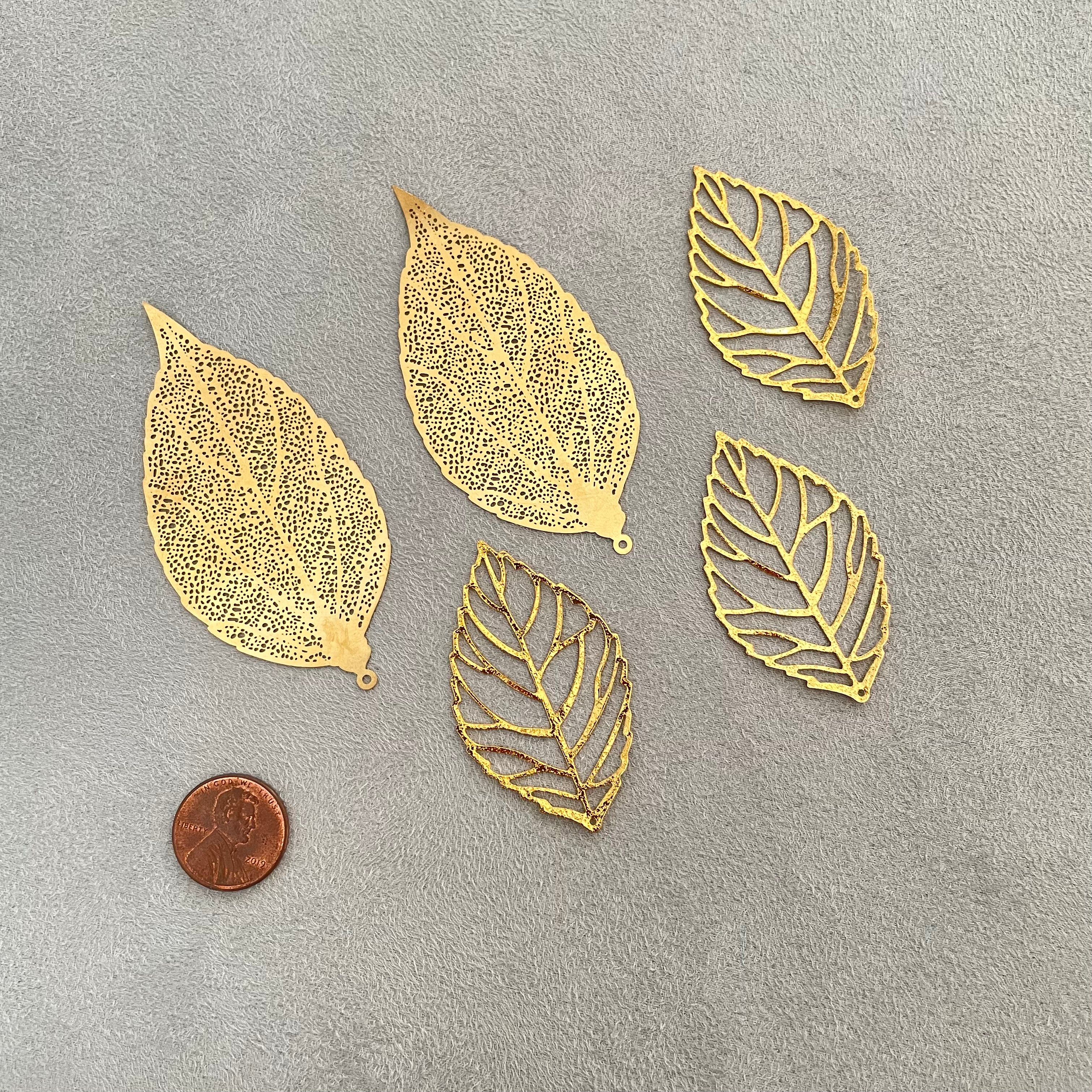 5 styling leaves including 3 gold leaves, 2 gold leaves that are larger, penny beside for size reference  - flat lay props from Champagne & GRIT