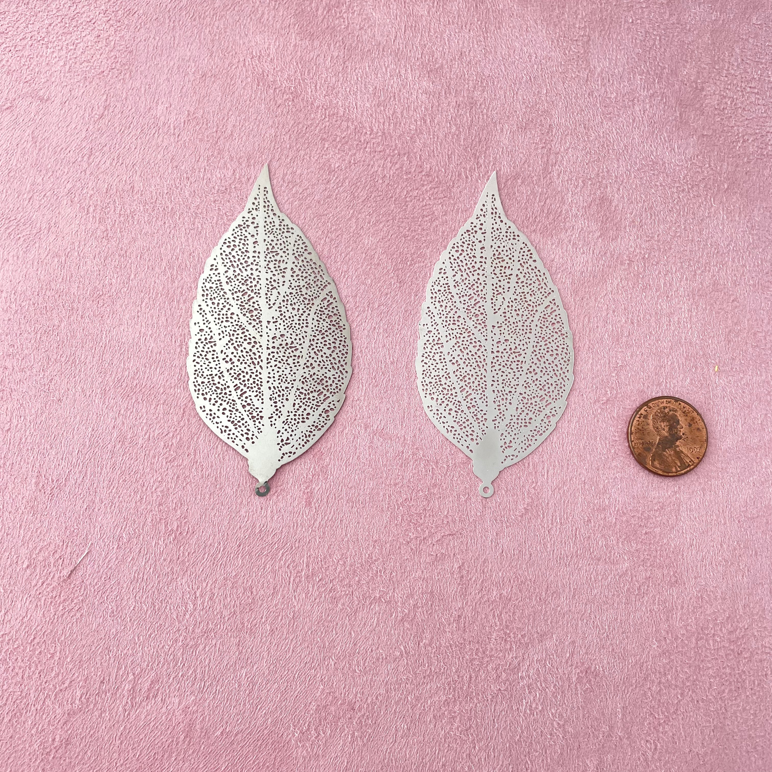 2 silver leaves that are larger with penny beside for size reference - wedding flat lay props from Champagne & GRIT