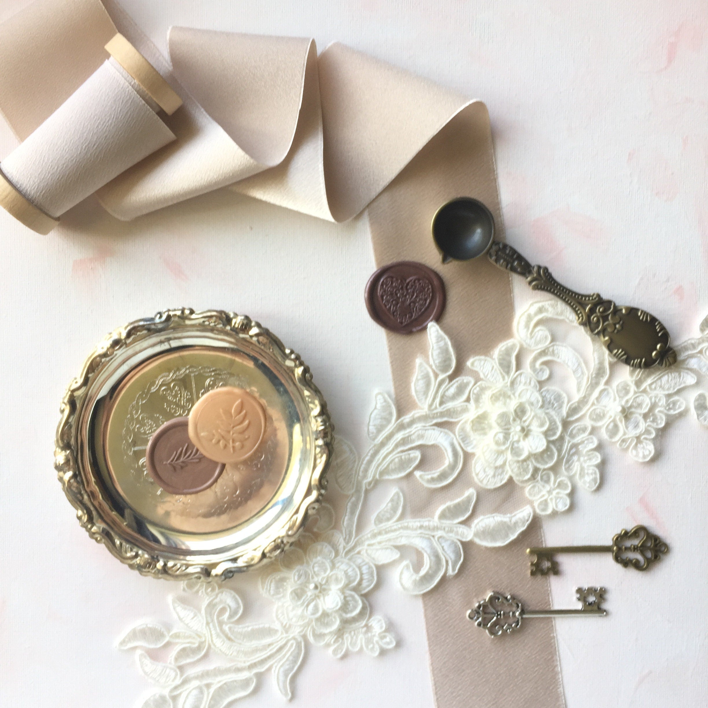 Vintage silver dish styled with wax seals, silver and gold keys, a piece of lace, vintage spoon and neutral ribbon - Wedding Flat lay props from Champagne & GRIT