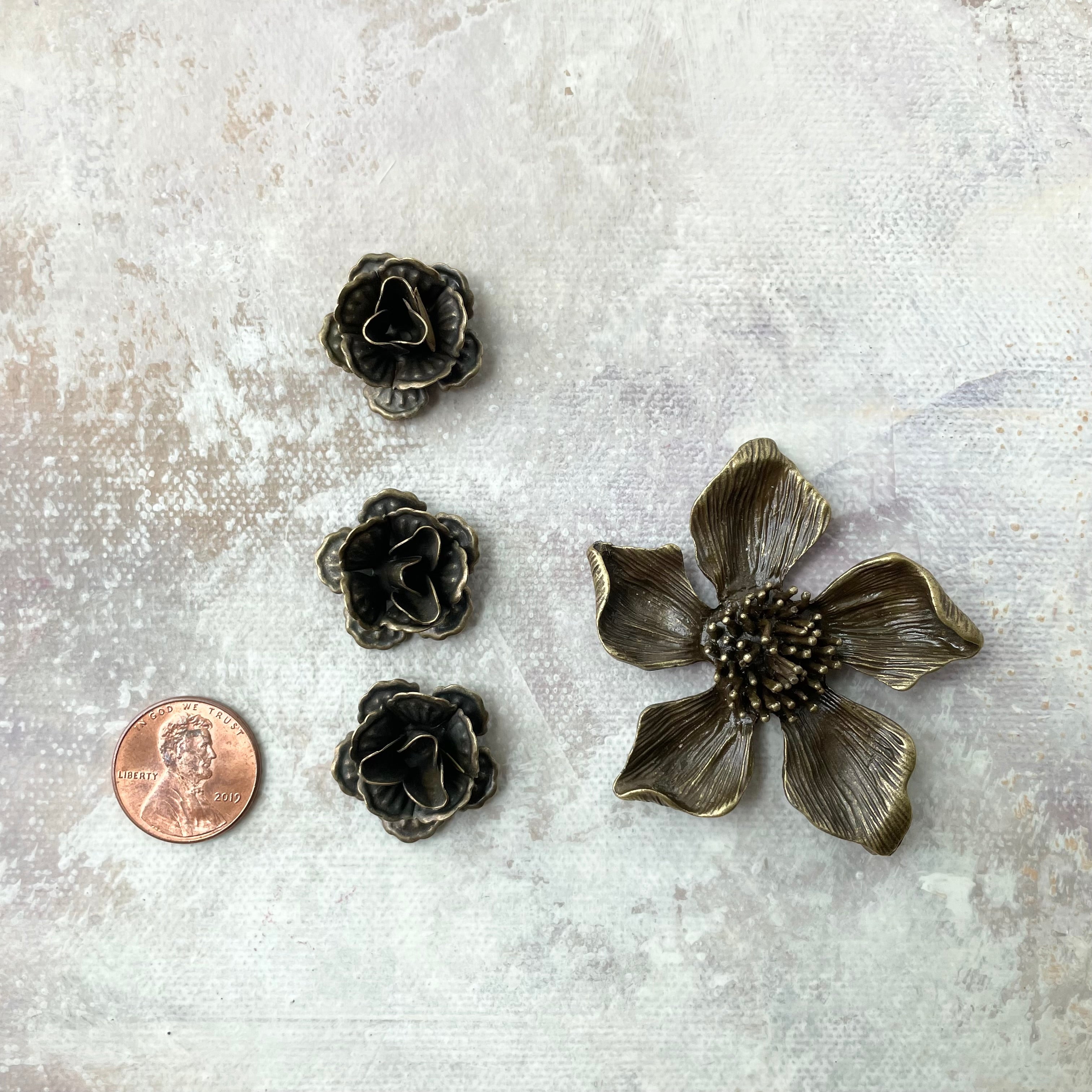 3 small metal styling flowers 1 larger metal styling flower with penny beside for size reference - flat lay props from Champagne & GRIT