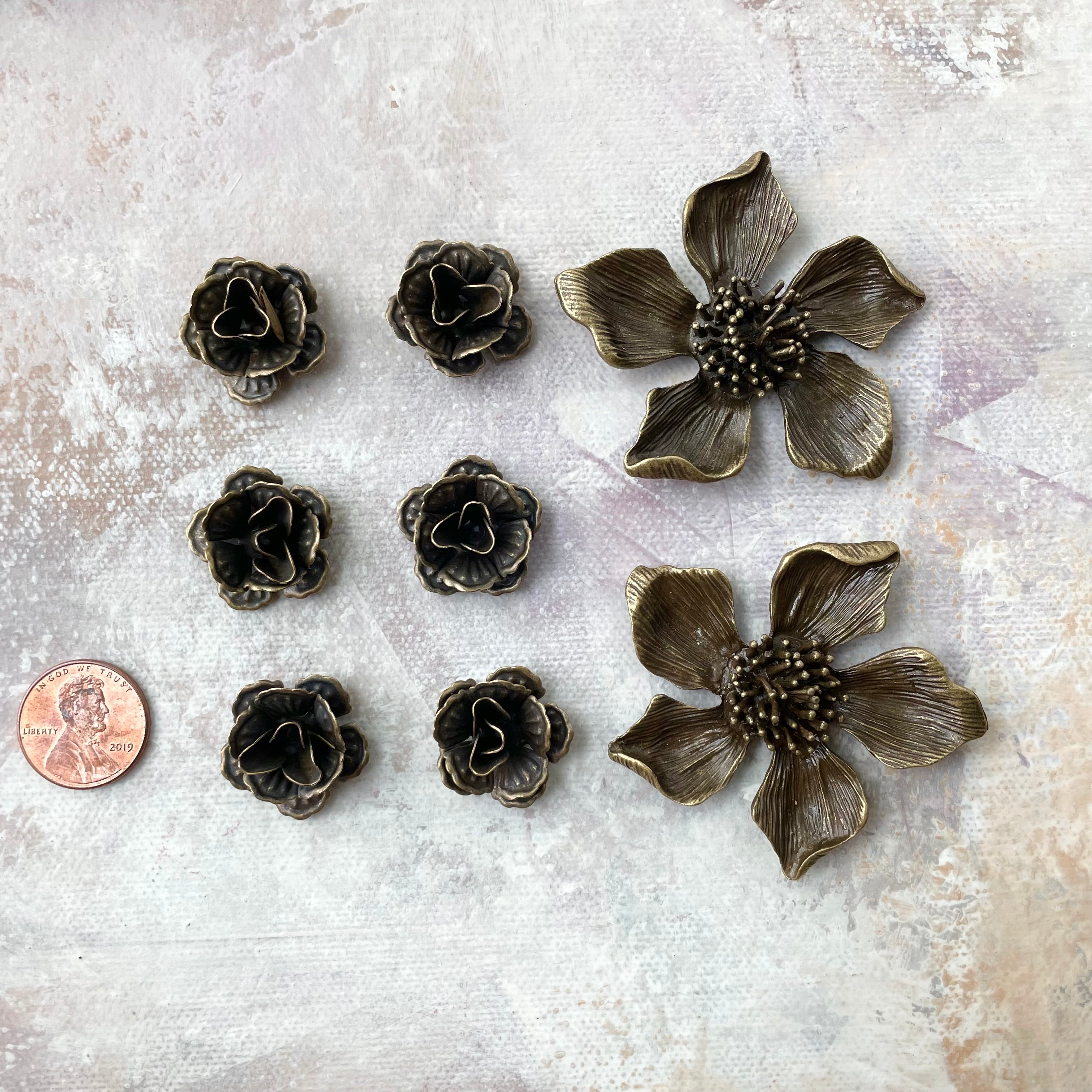 6 small metal styling flowers 2 larger metal styling flowers with penny beside for size reference - flat lay props from Champagne & GRIT